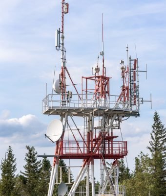 Red and white communication tower with TV and cellular antennas