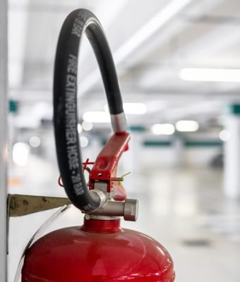 Extreme close-up of a fire extinguisher placed on the column of a car park