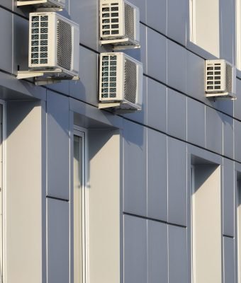Gray wall of office building made of metal plates with windows and air conditioners