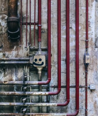 Photo of an old industrial wall of pipes and decay.