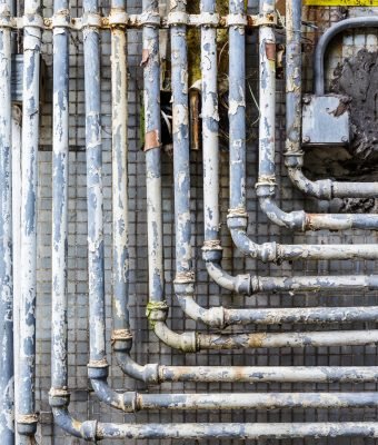 Series of parallel old pipes on wall